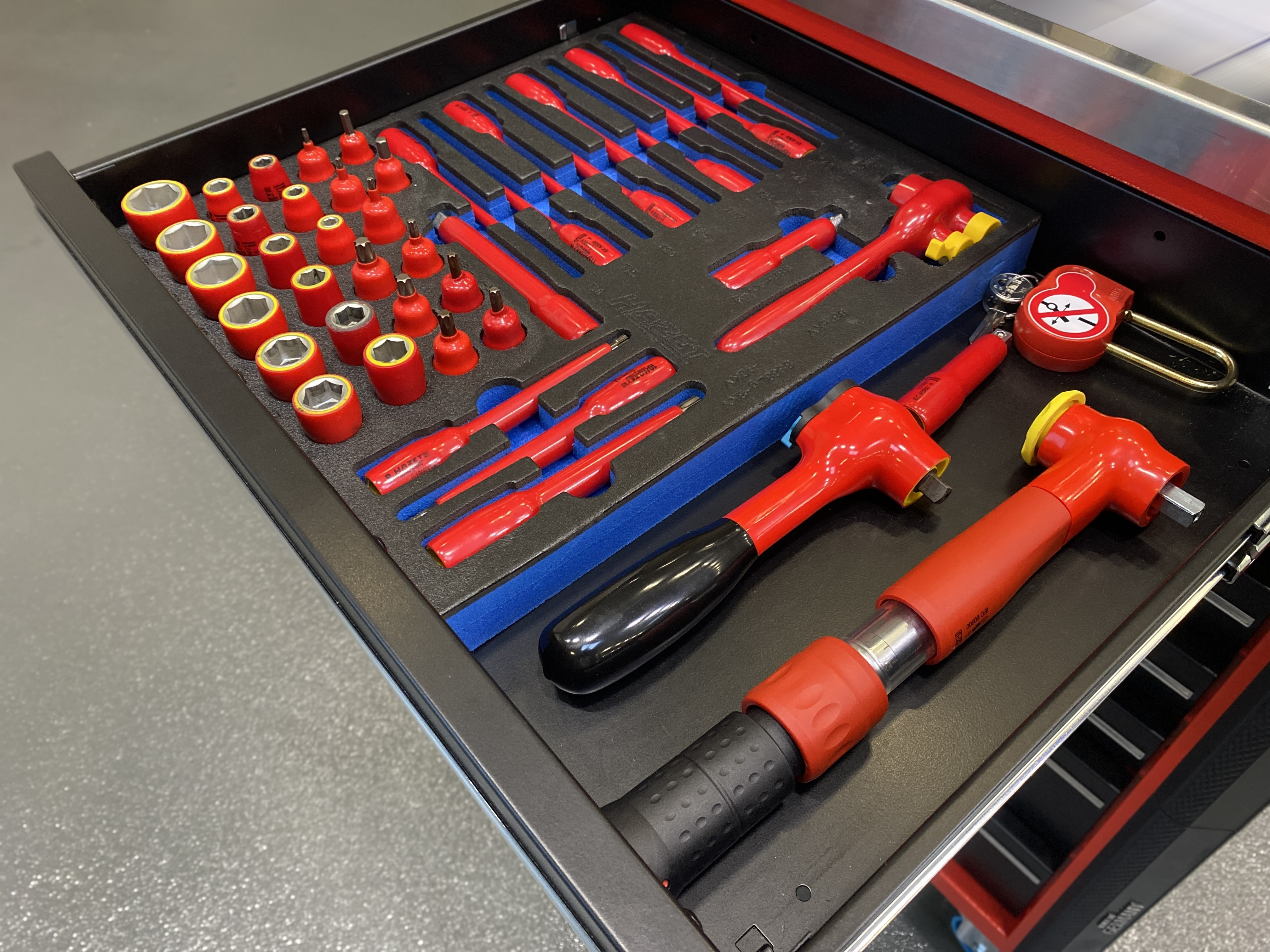 Schublade mit isoliertem Hochvolt-Werkzeugsatz, darunter Stecknüsse, Schraubendreher und Spezialwerkzeuge, geprüft und ausgelegt für Arbeiten an spannungsführenden HV-Systemen.